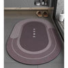 A round, gray bath mat with concentric rings and the word HOME printed on it, placed on a tiled floor.