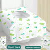 A white disposable toilet seat cover with green accents is shown on a toilet, packaged for travel.