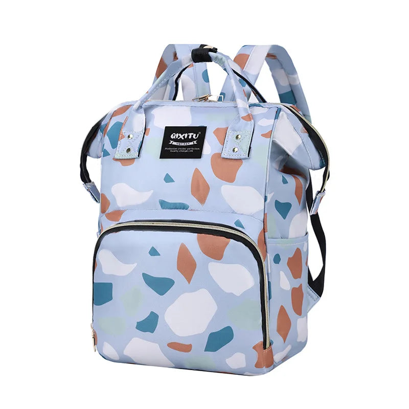 A light blue and white patterned waterproof diaper bag backpack with black straps and storage pockets.