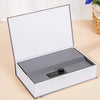 A silver and black hidden book safe with a combination lock displayed open on a light wooden surface.