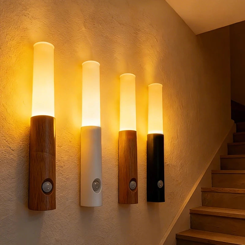 A row of four magnetic LED wall lights with wooden bases and illuminated cylindrical shades mounted on a beige wall.