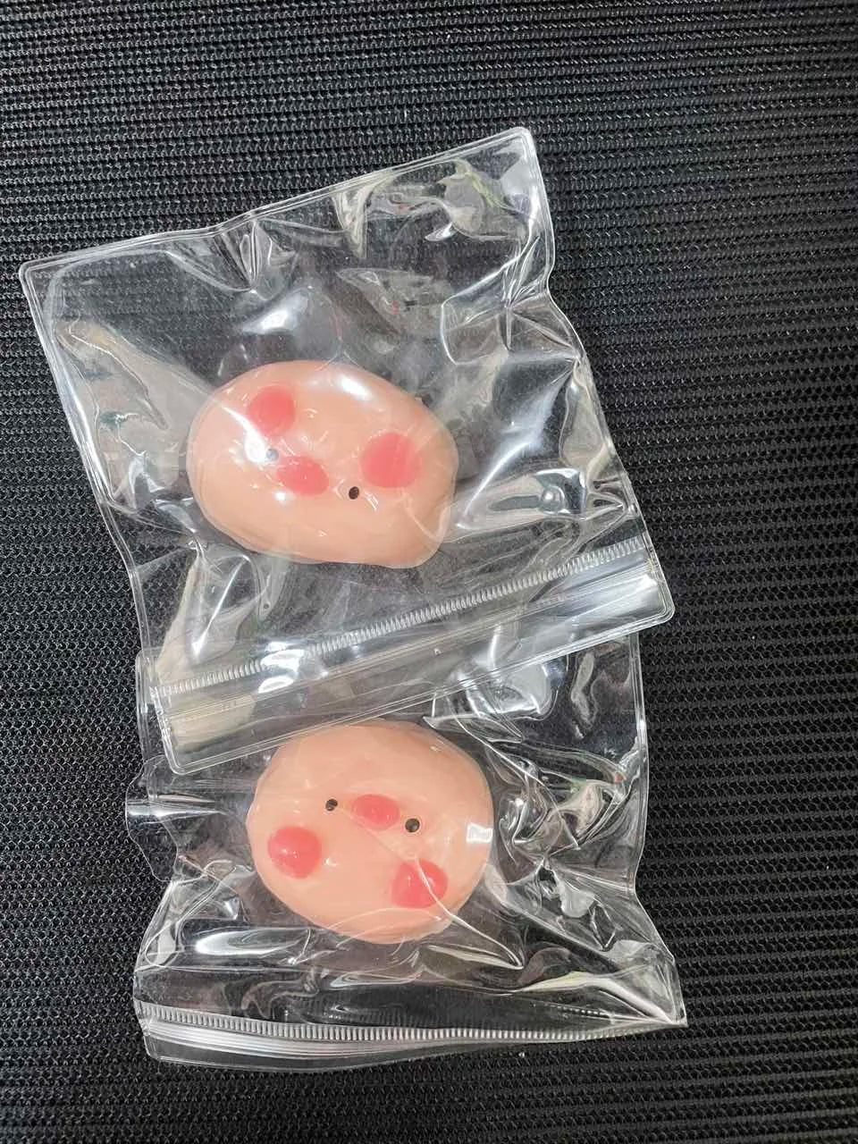 A pink pig squishy stress relief toy is visible inside a clear plastic sealed pouch.