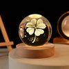 Laser engraved crystal ball night light with a four-leaf clover design on a wooden base