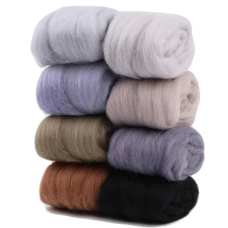 A stack of eight colored wool roving packs for needle felting, showing various shades of gray, brown, and black.