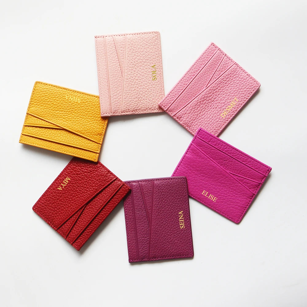 A collection of six genuine leather slim card holder wallets in various shades of pink and magenta arranged in a circle.