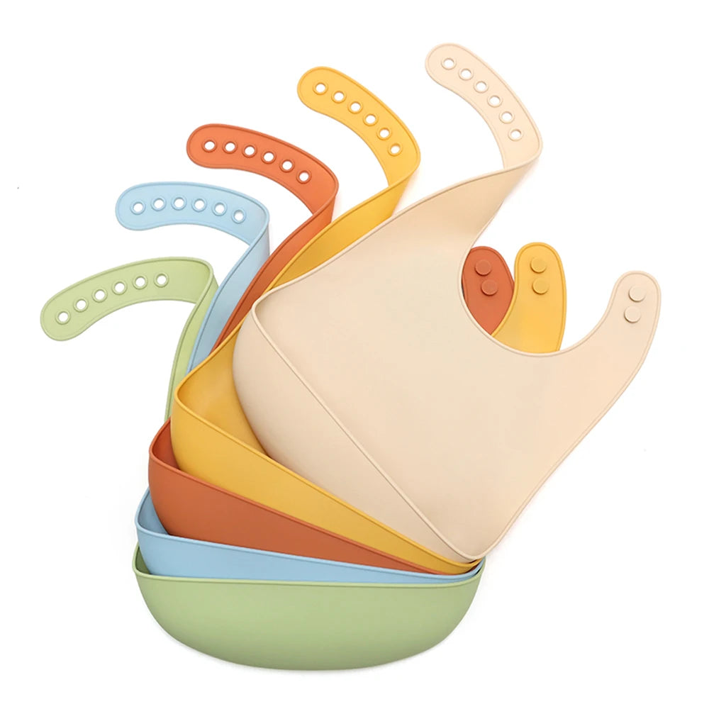 A stack of silicone baby bibs in various pastel colors, including orange, yellow, and green.