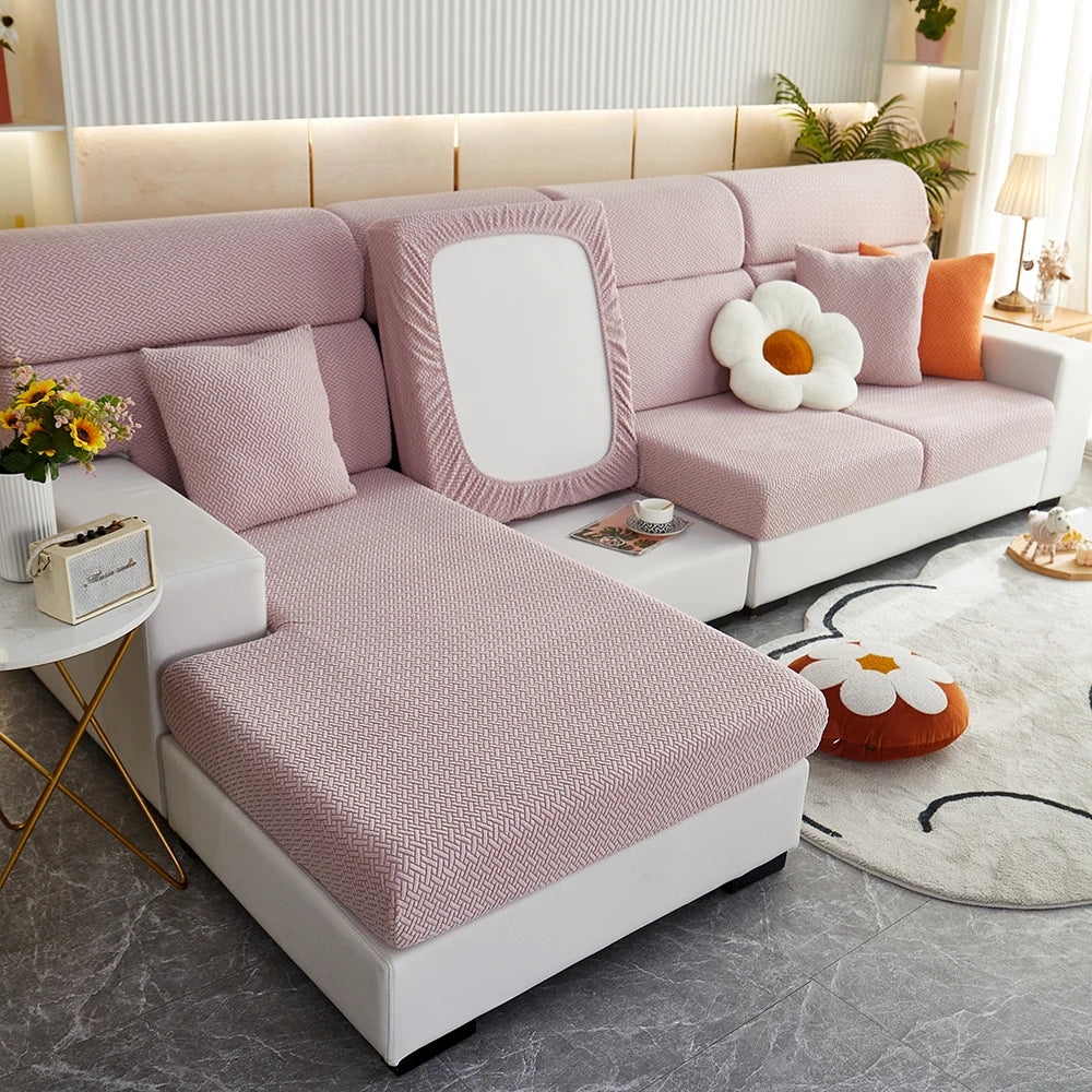 A light pink elegant jacquard sofa slipcover with white cushions and orange accents in a modern living room setting.