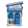 A miniature house facade kit painted in blue and white with a wooden roof and blue door.