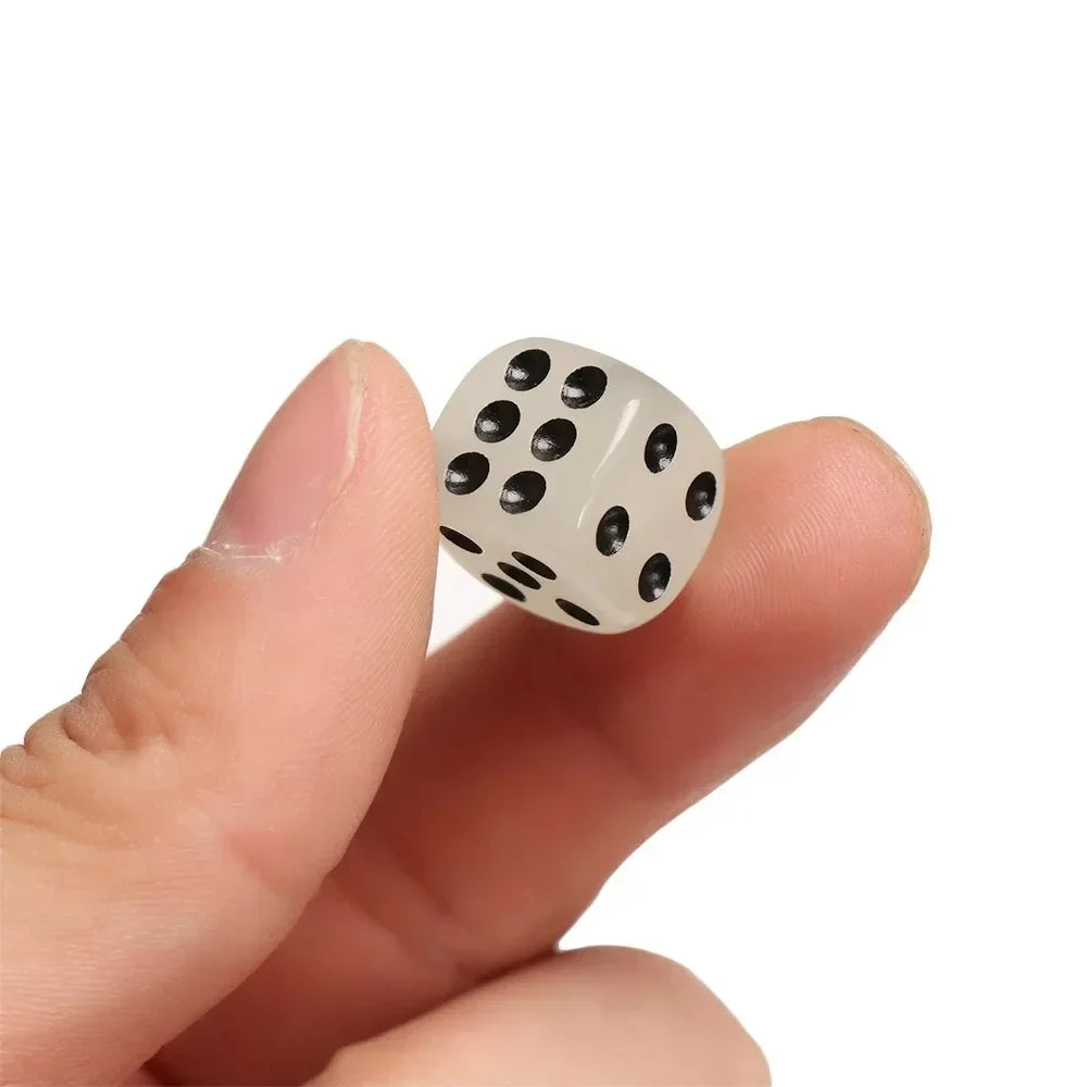 A hand holds a white glow-in-the-dark acrylic dice set with black dots against a white background.