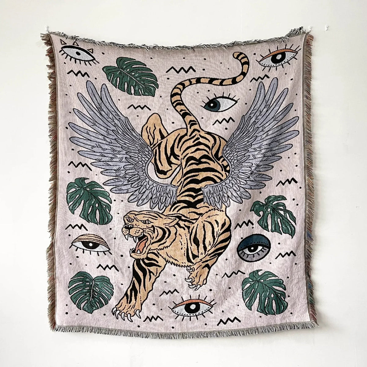 A woven throw blanket featuring a bohemian design with tiger and leaf motifs in muted earth tones.