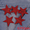 A set of five red glitter star iron-on embroidered patches placed on a denim fabric background.