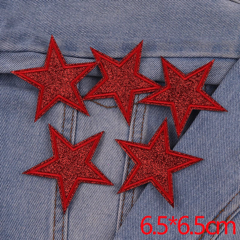 A set of five red glitter star iron-on embroidered patches placed on a denim fabric background.