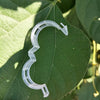 Clear reusable plastic plant clips used for garden support and vine fixing placed on a green leaf.