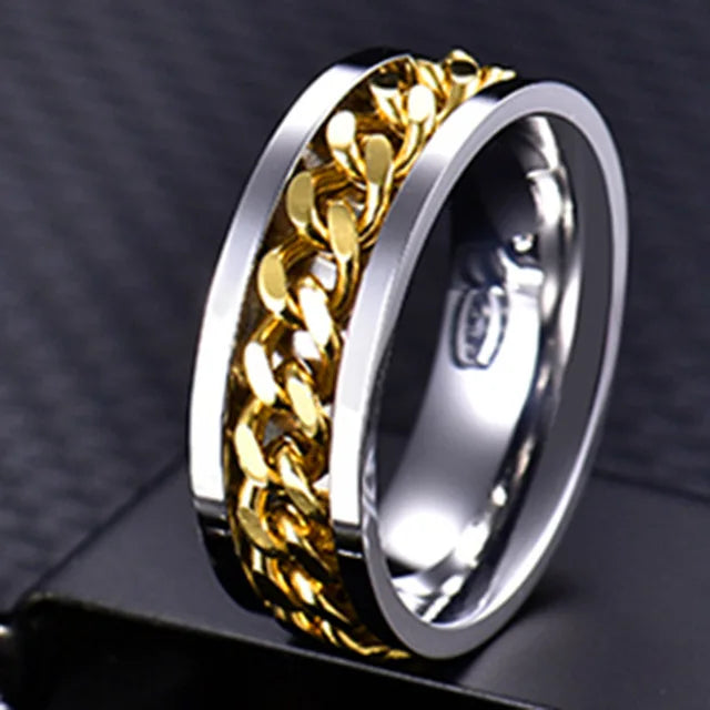 A close-up of a stainless steel spinner ring with a gold-colored chain design.