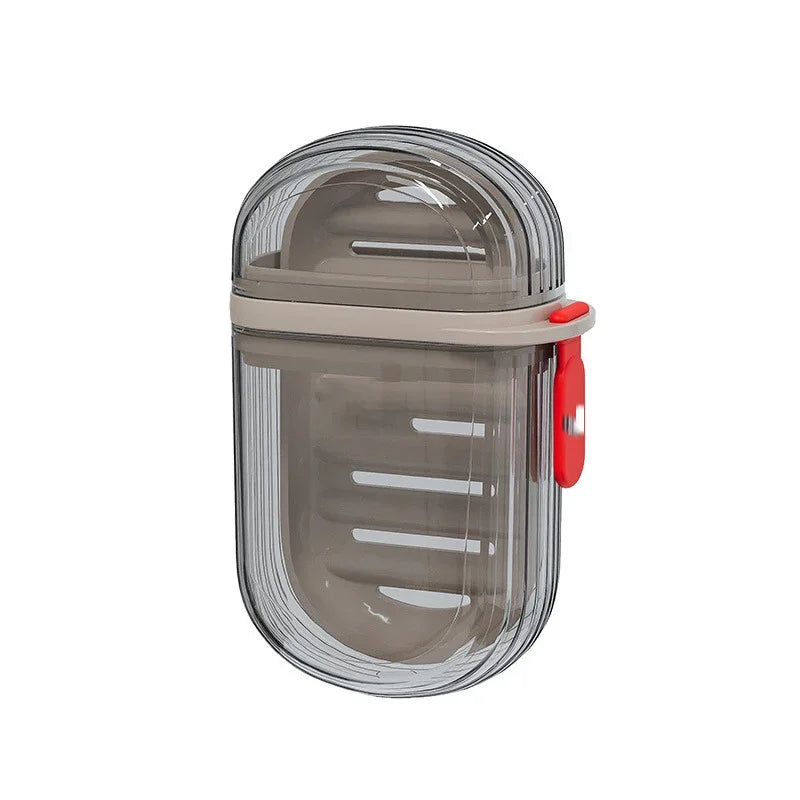 A clear plastic portable travel soap box with a drainage lid and a red handle.