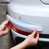 Hands are installing white and orange anti-collision bumper protector strips on a car's corner.