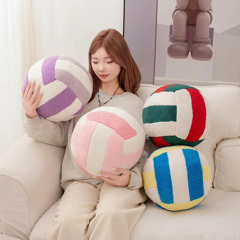 A woman is holding several colorful simulation volleyball plush toys on a white sofa.