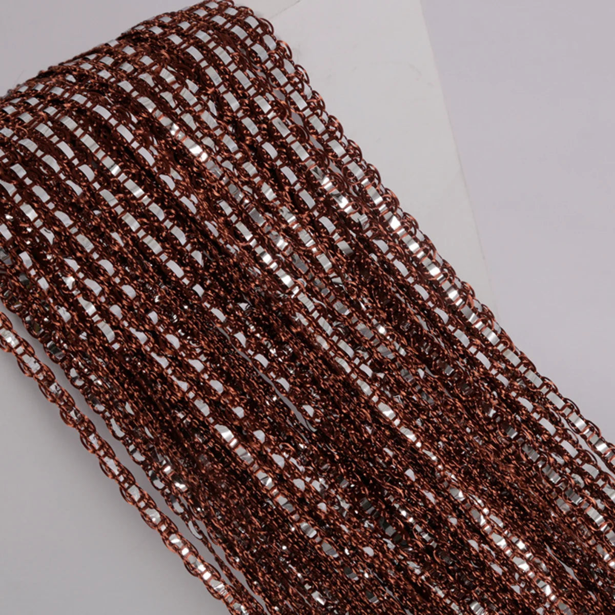 A close-up of a brown metallic boho tassel string curtain with small clear accents.
