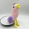 A pink plush toy of an Opila bird with yellow accents and purple feet standing on a white circular base.