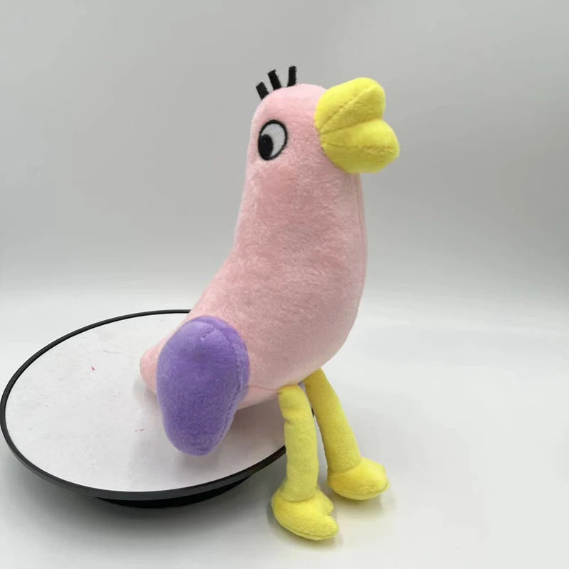 A pink plush toy of an Opila bird with yellow accents and purple feet standing on a white circular base.