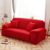 A vibrant red silky soft stretchable sofa cover displayed on a light wooden floor near a window.