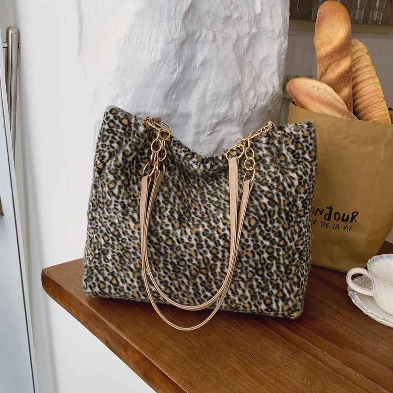 Sac en toile à imprimé léopard avec anses en cuir beige posé sur une surface en bois à côté d'un sac en papier brun de pain.