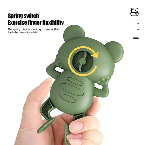 A hand holds a green silicone spring switch exercise finger flexibility toy shaped like a frog.