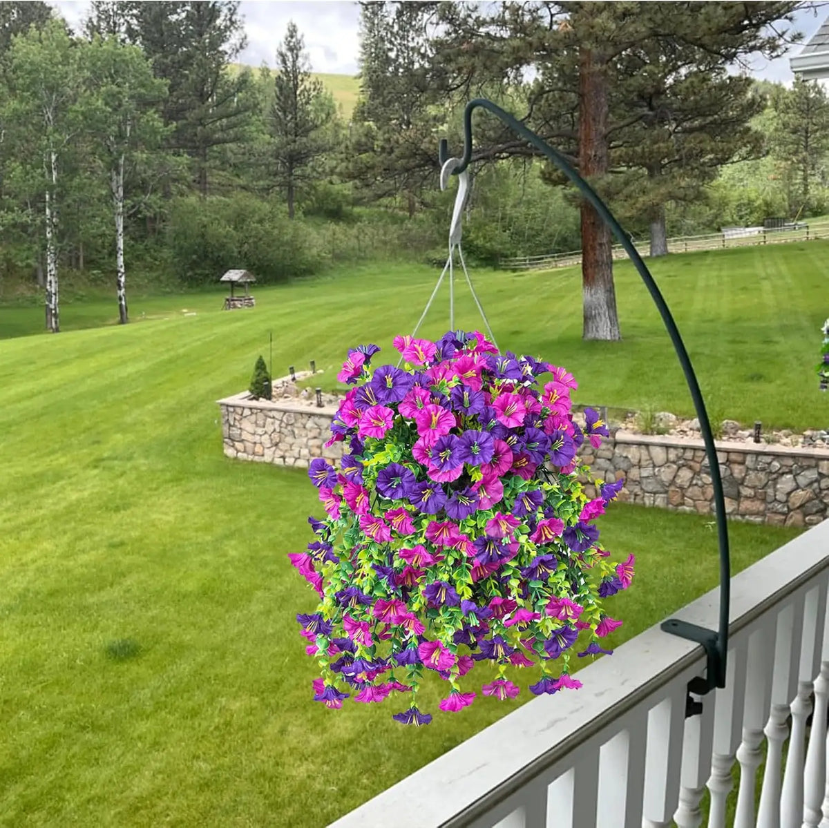 Una enredadera de flores artificiales moradas y rosas cuelga de una estructura metálica curva en un entorno exterior de céspe
