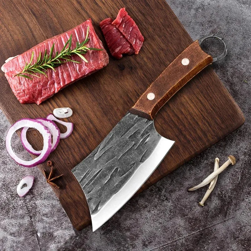 A stainless steel kitchen cleaver with a wooden handle rests on a cutting board surrounded by raw meat and garlic.