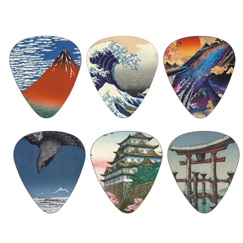 A set of twelve guitar picks featuring images of Mount Fuji, a large wave, a sunset, an eagle, a Japanese temple, and a torii