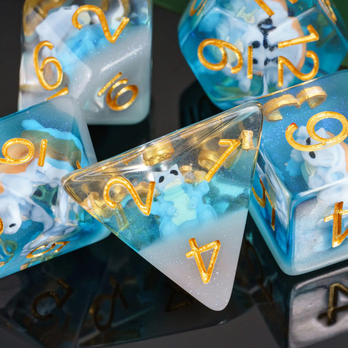 A close-up of a set of translucent blue and white resin dice, including a triangular die, resting on a dark reflective surfac
