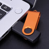 A portable orange USB flash drive is shown next to a silver laptop keyboard.