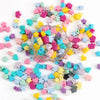 A scattered collection of colorful silicone crown star heart beads in various shades of pink, purple, yellow, blue, and green