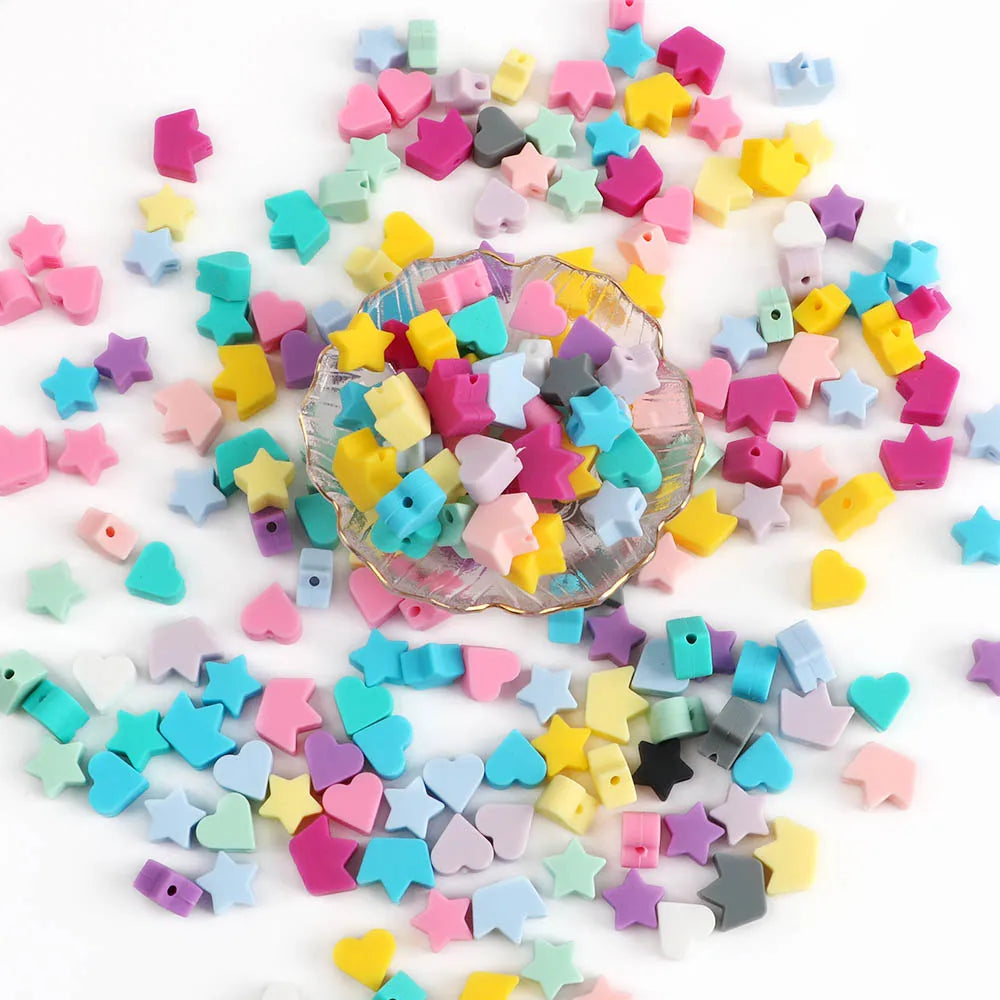 A scattered collection of colorful silicone crown star heart beads in various shades of pink, purple, yellow, blue, and green