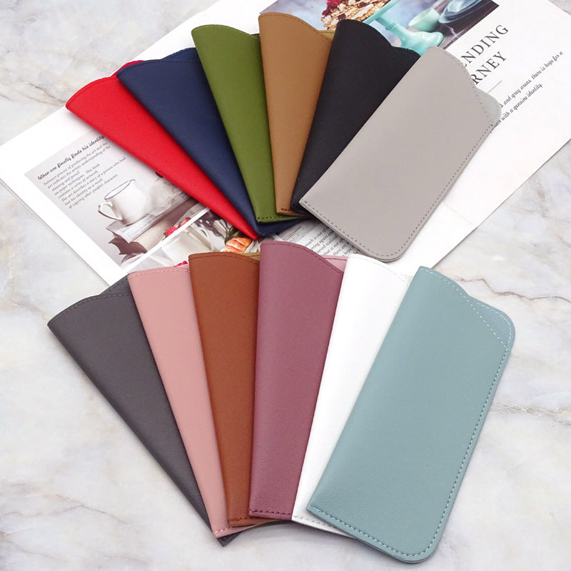 Colección de fundas protectoras para gafas de cuero PU en tonos verdes, rosa, marrón y gris sobre una superficie blanca