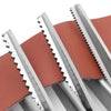 Close-up view of stainless steel pinking shears with serrated edges against a reddish fabric background.