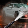 A hand holds an adjustable high-pressure car wash water spray gun spraying water onto a white car.