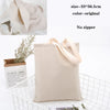 A beige foldable canvas tote bag with light pink handles is shown next to a small potted plant.