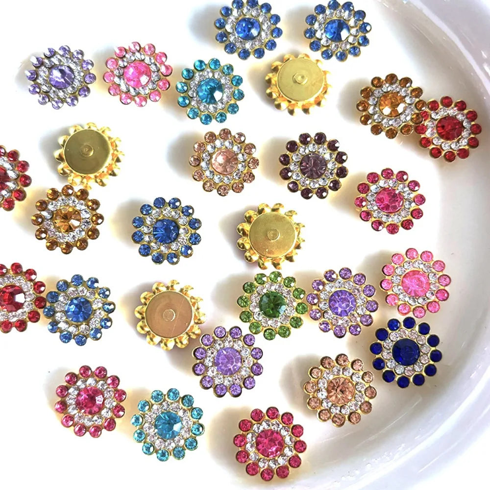 A collection of multicolor sew-on flower rhinestones in various shades of pink, blue, and gold arranged on a white surface.