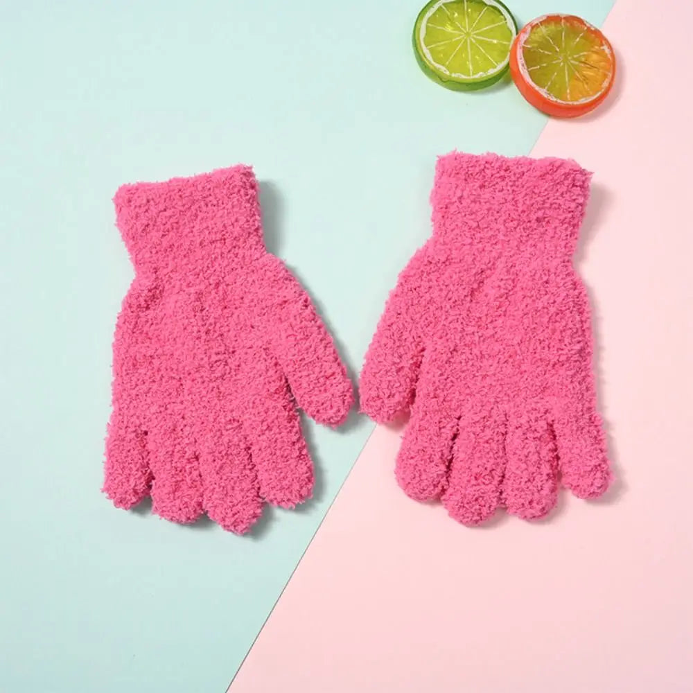 Pair of bright pink plush winter gloves for kids resting on a light blue and pink background.