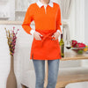An orange classic half apron with pockets worn by a person, standing in a bright indoor setting.