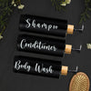 Three black glass refillable bottles for shampoo, conditioner, and body wash with wooden pump tops.