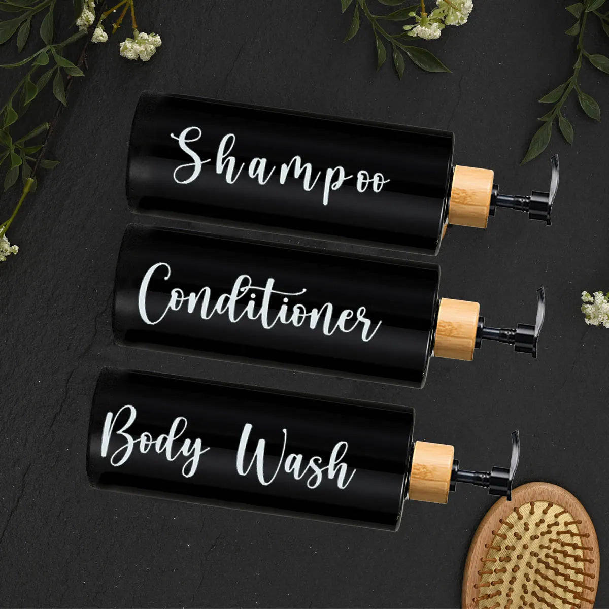 Three black glass refillable bottles for shampoo, conditioner, and body wash with wooden pump tops.
