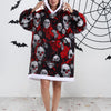 Eine Frau trägt einen schwarz-roten Schädelmuster-Patchwork-Oversized-Fleece-Hoodie mit weißer Kapuze vor einem Spiel...