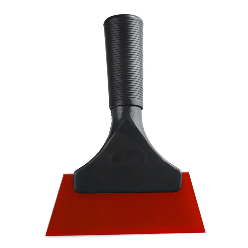 A black car window squeegee with a soft rubber blade resting on a red surface.