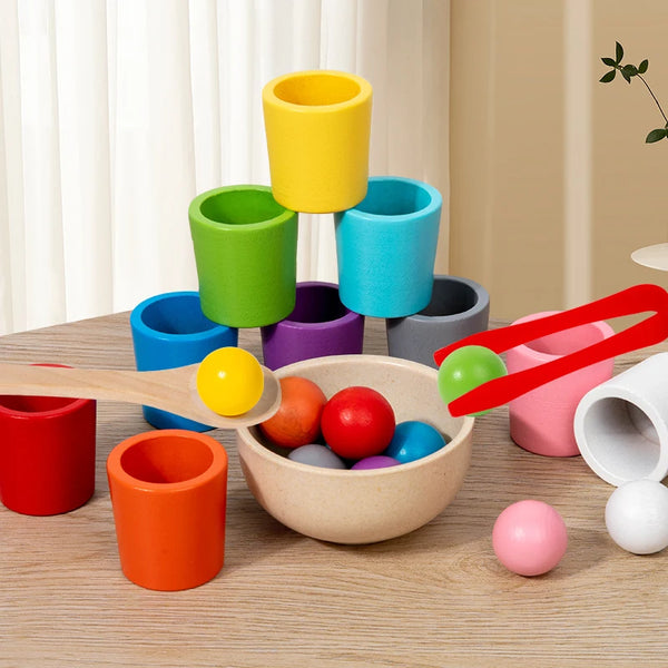 A collection of colorful wooden stacking cups and balls arranged on a light wooden surface.
