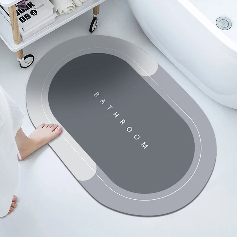 A gray bathroom mat with the word BATHROOM embossed on it is placed next to a white toilet bowl.
