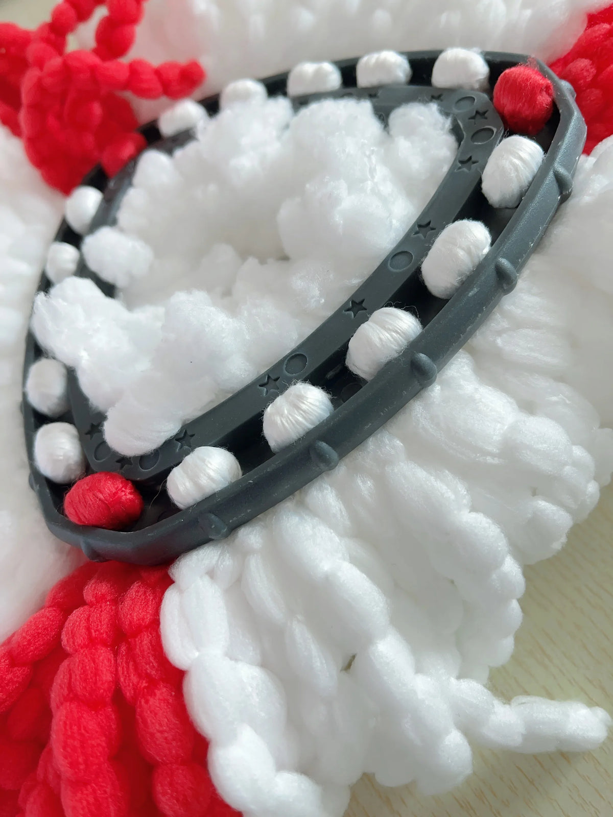 A close-up of a black and white microfiber mop pad replacement with red yarn accents.