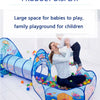 A woman is playing with a child in a colorful ball pit play tent and crawl tunnel for children.