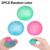 Two random colored soft textured stress balls are shown in a hand.